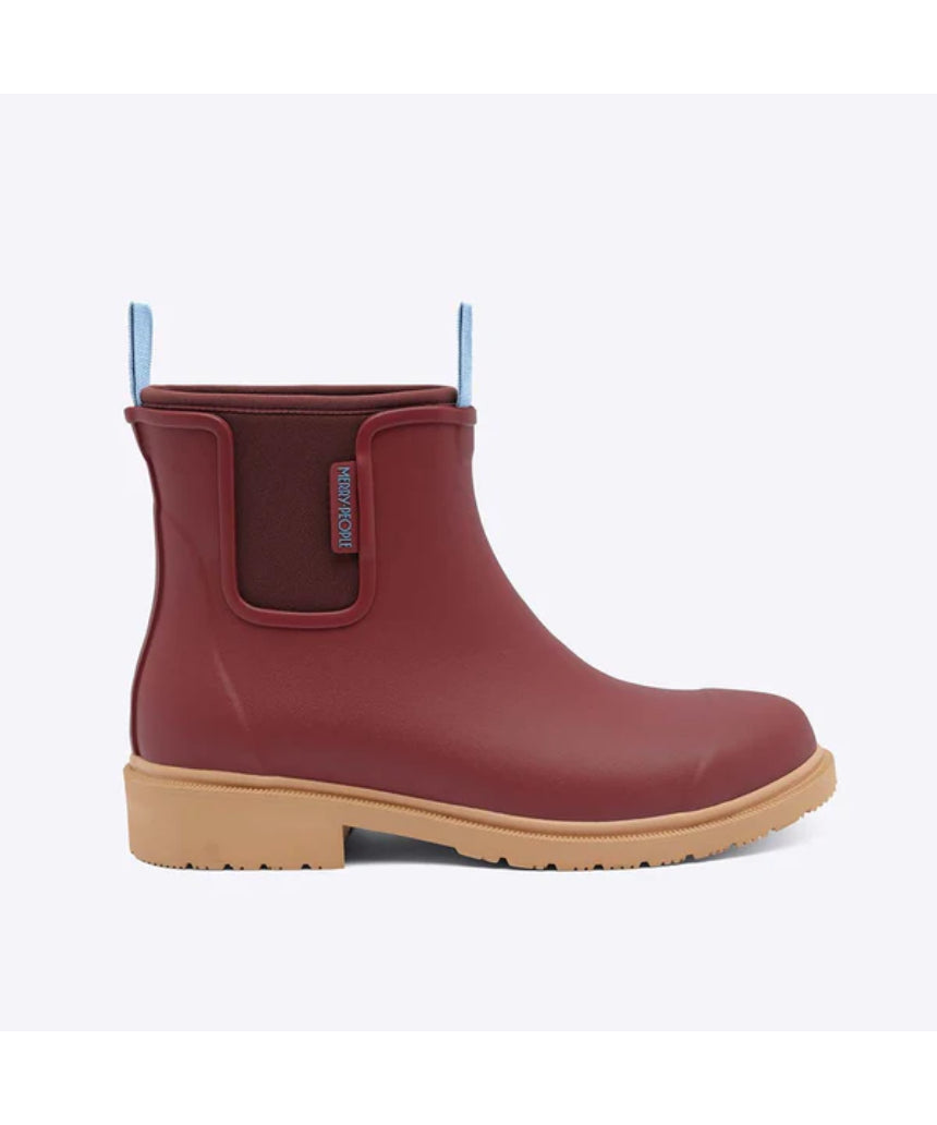 Brick red Merry People Bobbi gumboots shown from the side, featuring waterproof rubber and stylish design for rainy weather.