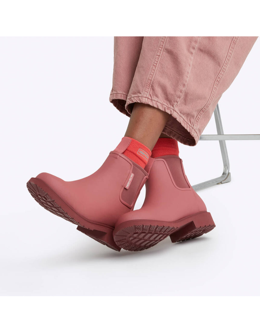 Merry People Bobbi Gumboot in clay color, stylish waterproof rubber boots with a textured sole, sitting outdoors.