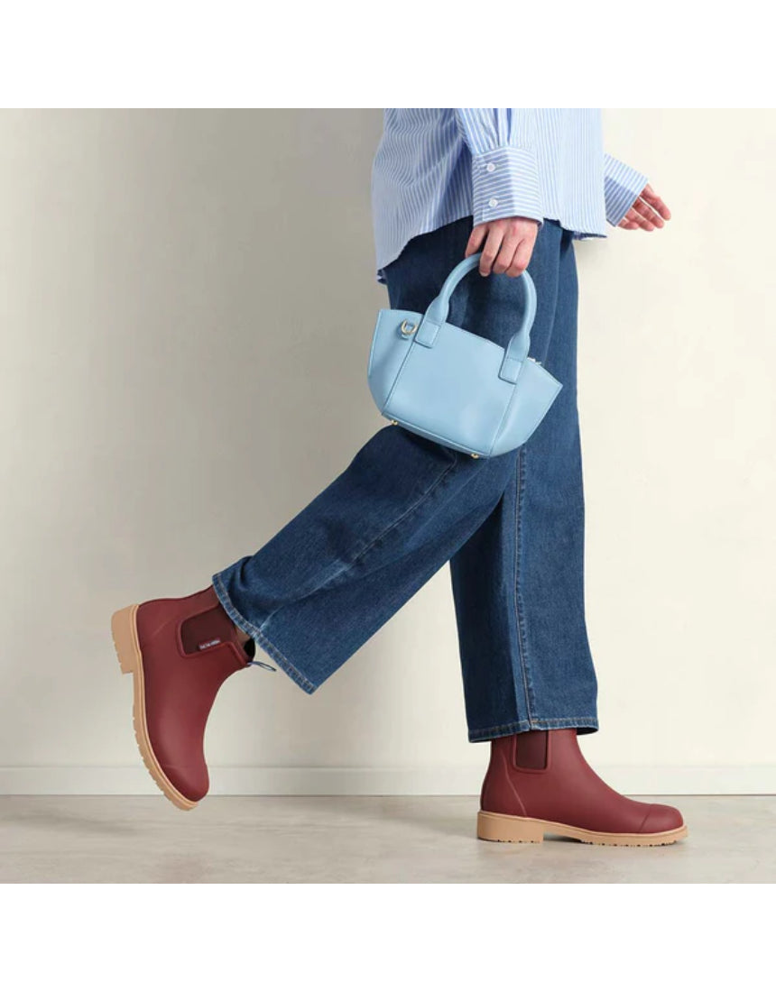 Merry People Bobbi Gumboots in brick red worn by a model, showcasing stylish waterproof footwear for rainy weather