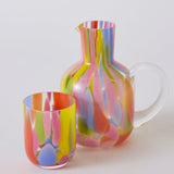 Kip & Co Festiva carafe and glass set on a table with vibrant, colorful patterns, showcasing stylish drinkware design.
