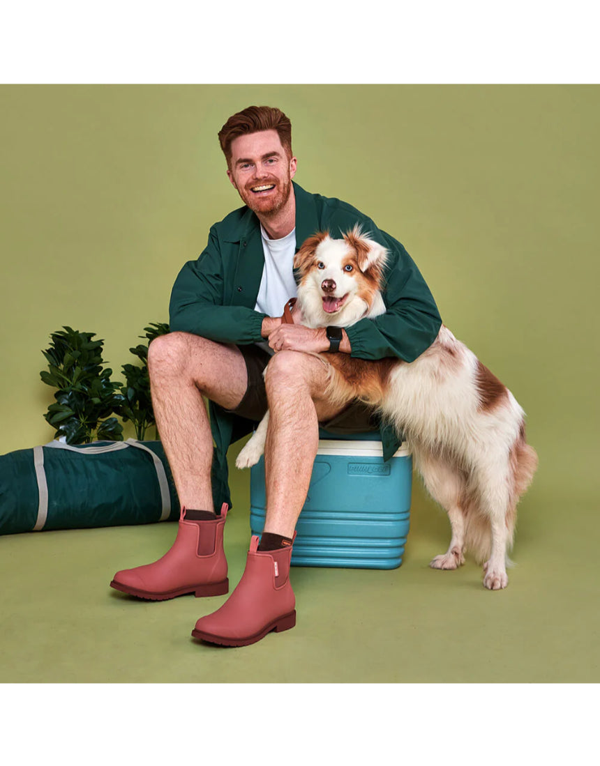 Merry People Bobbi gumboots in clay color, stylish waterproof rubber boots for rainy days, shown in outdoor lifestyle setting.