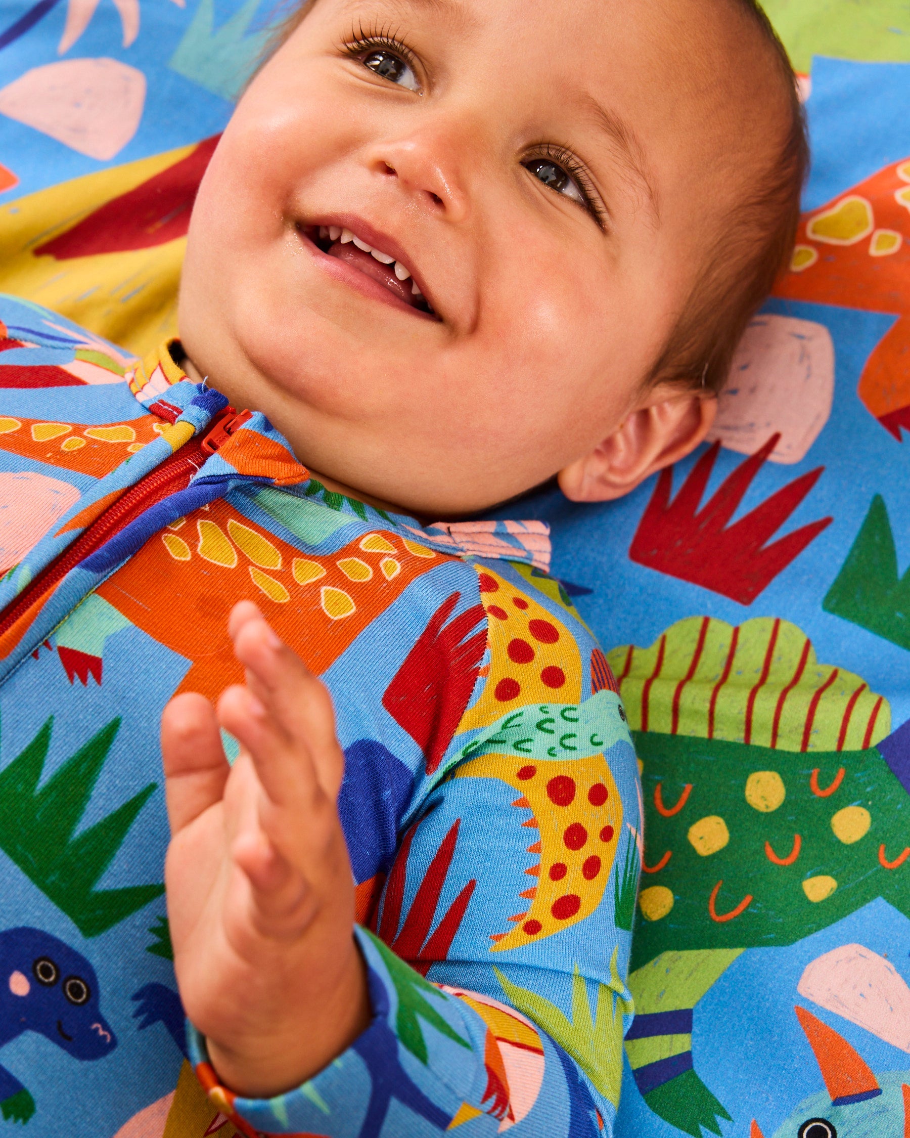 Kip & Co Dinosaur Roar organic long sleeve baby romper with zipper, featuring colorful dinosaur print and cozy fabric for infants.