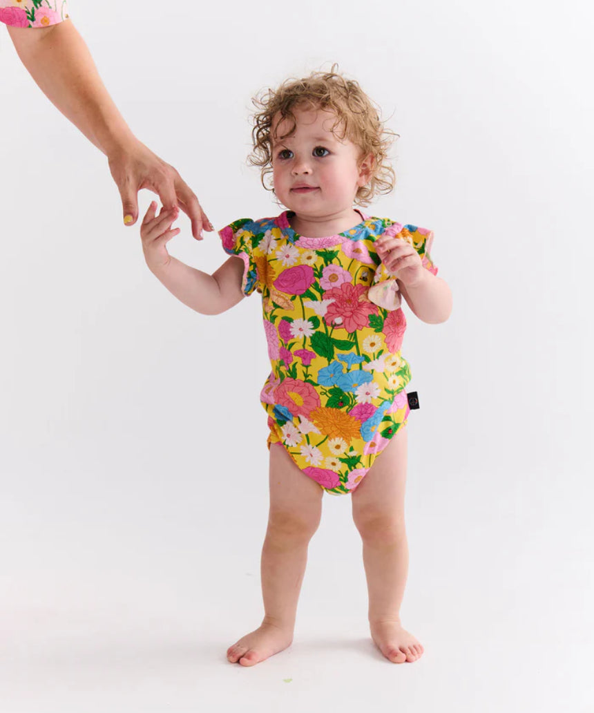 Kip & Co baby girl short sleeve frill romper with sun-themed pattern, soft fabric, and cute ruffle details.