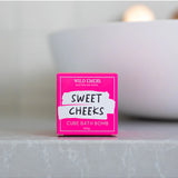 Wild Emery Sweet Cheeks Bath Bomb in vibrant pink and purple colors, designed for a relaxing bath experience.