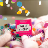 Wild Emery Sweet Cheeks Bath Bomb from the Bath & Body collection, showing a colorful, round bath bomb with a textured surface.
