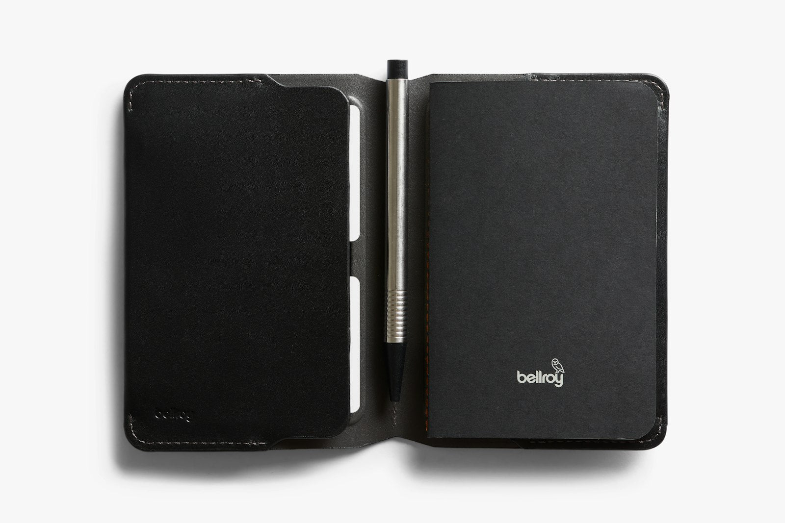 Bellroy black notebook cover open to reveal interior slots and pen holder, made from smooth leather.