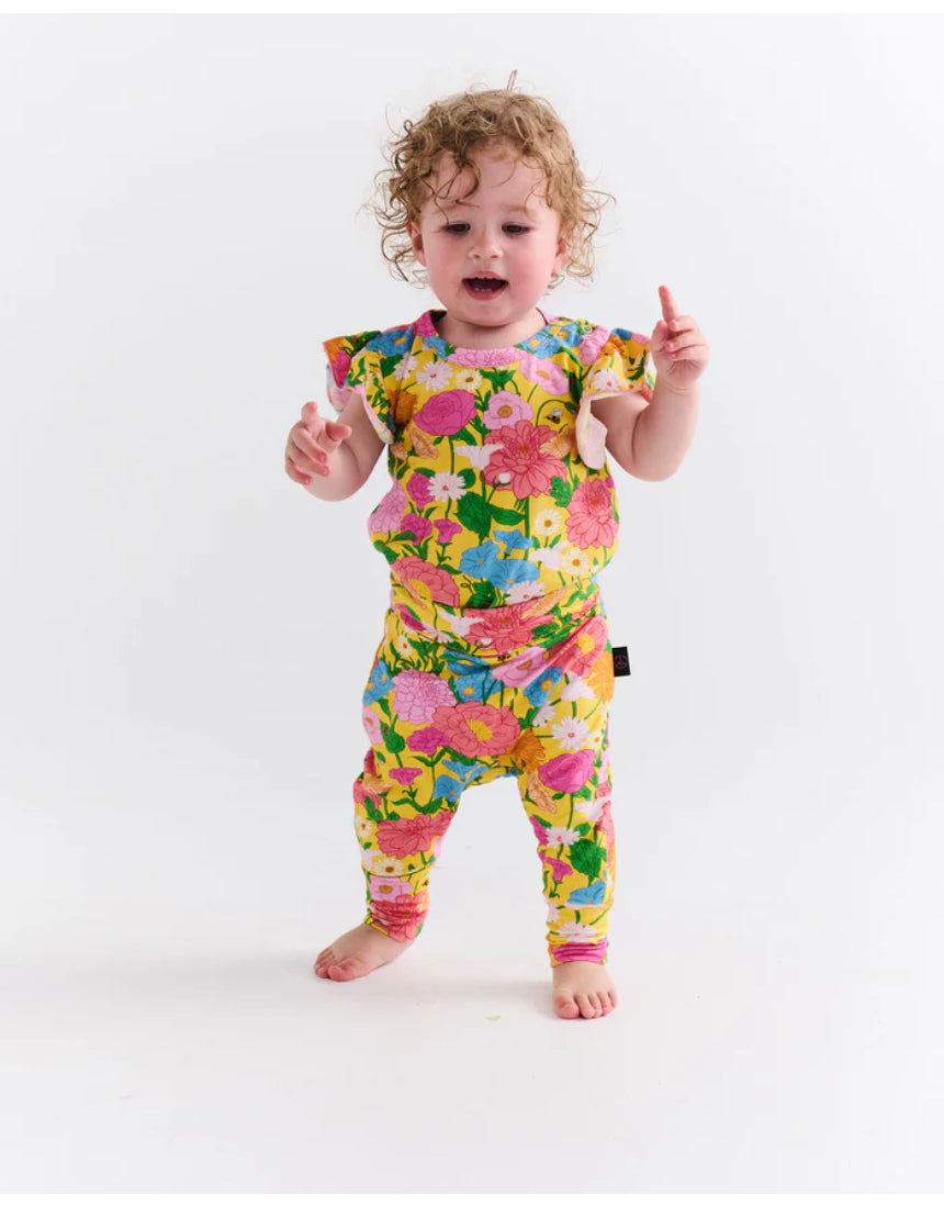 Kip & Co baby clothing Follow the Sun short sleeve frill romper with colorful patterns and ruffled details on a white background.