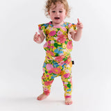 Kip & Co baby clothing Follow the Sun short sleeve frill romper with colorful patterns and ruffled details on a white background.