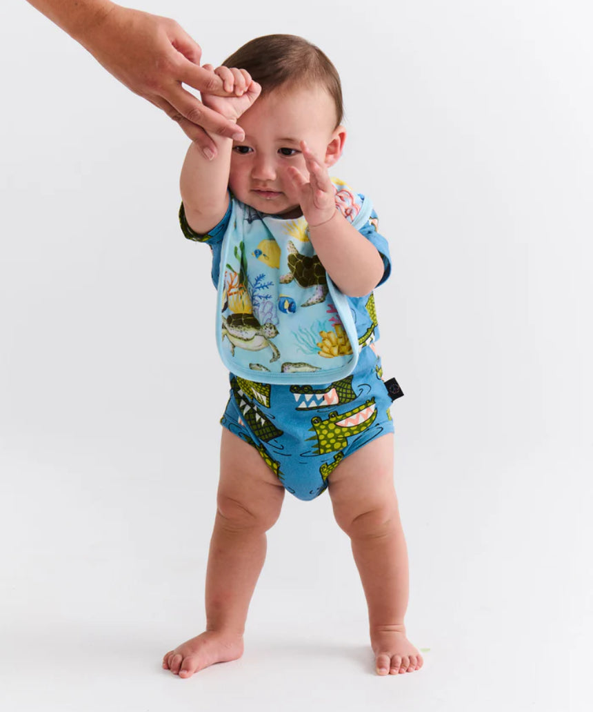 Kip & Co Reef Life cotton baby bib with colorful reef print, soft fabric, and adjustable neck closure for comfortable feeding.