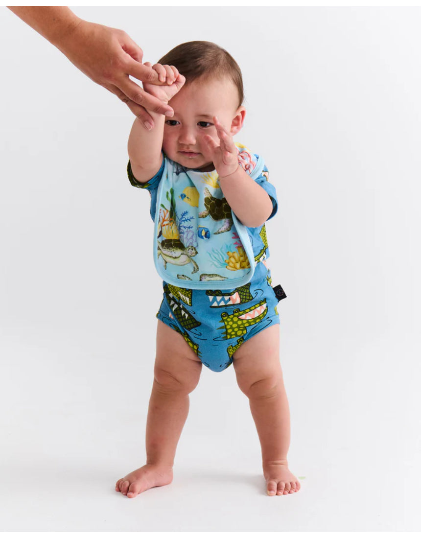 Kip & Co Reef Life cotton baby bib with colorful reef print, soft fabric, and adjustable neck closure for comfortable feeding.