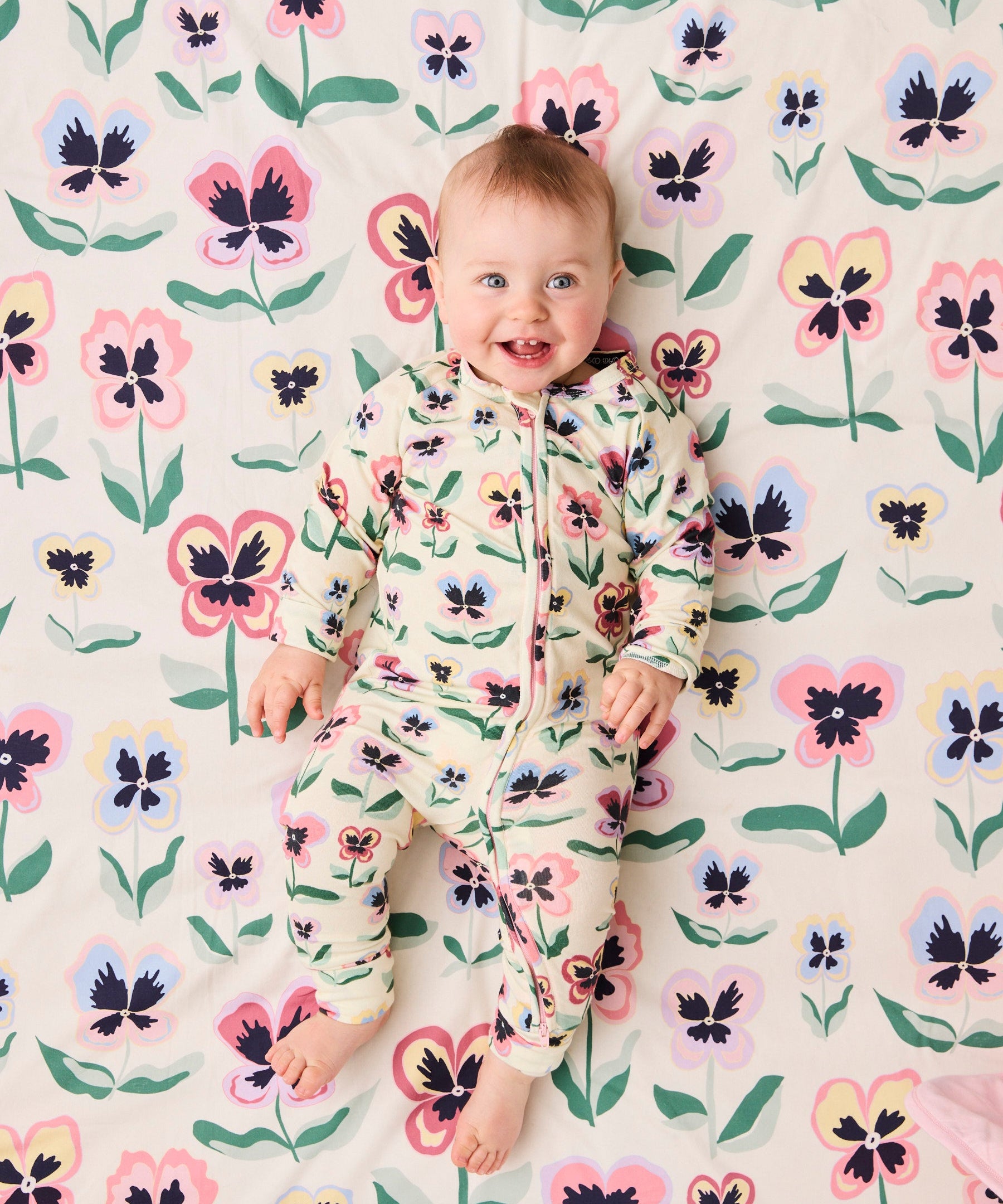 Kip & Co Pretty Pansy organic long sleeve zip romper for babies, featuring floral print and soft cotton fabric.