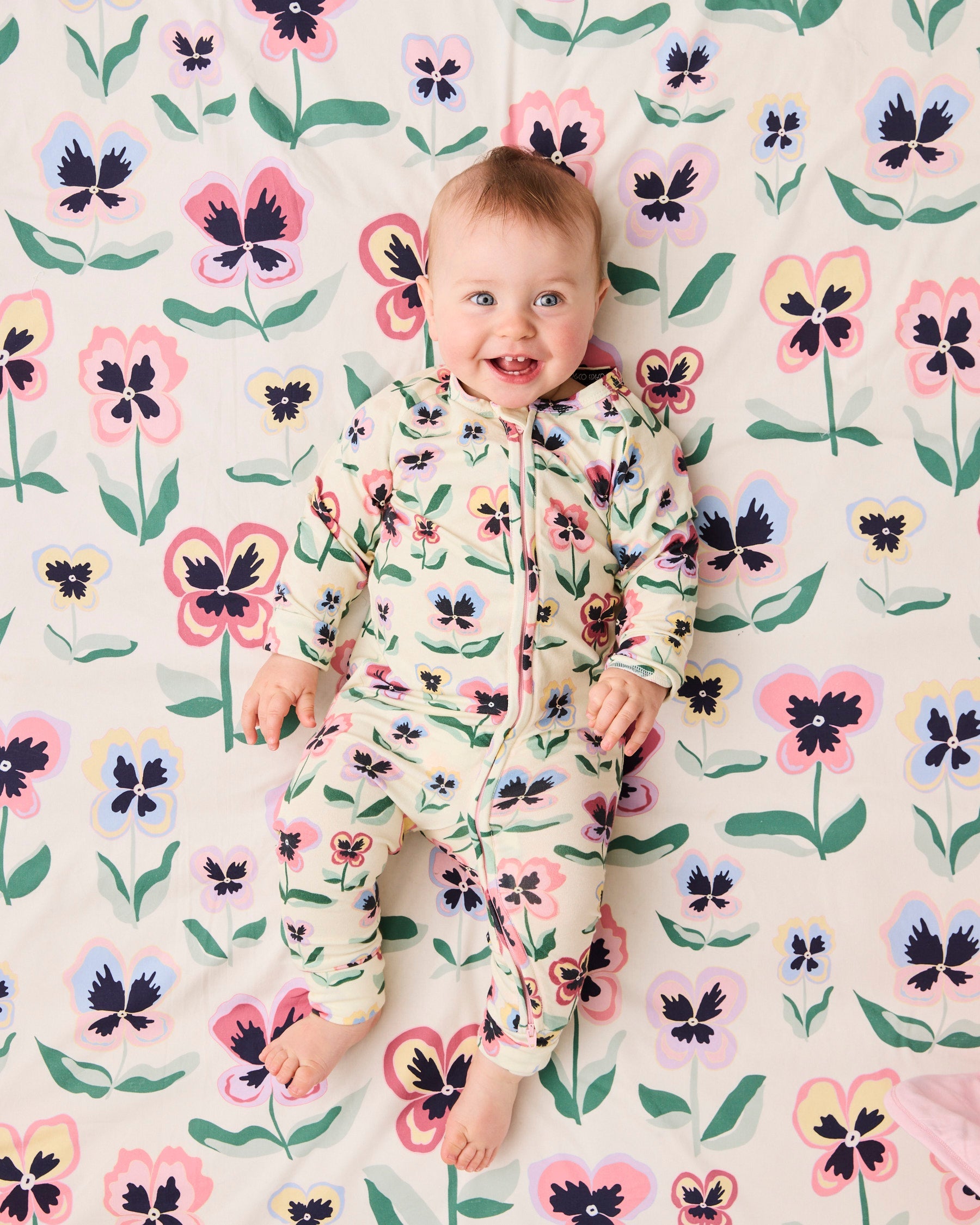 Kip & Co Pretty Pansy organic long sleeve zip romper for babies, featuring floral print and soft cotton fabric.