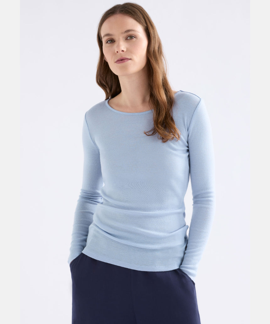 Elk Merino long sleeve top in pearl blue, lightweight, soft wool clothing with a fitted design, displayed on a hanger.