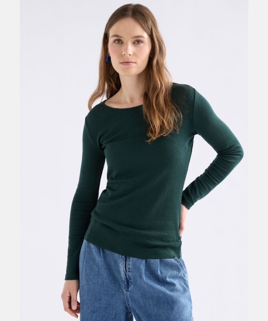 Elk Merino long sleeve top in dark pine color, lightweight and soft, shown on a hanger with a close-up of the fabric texture.
