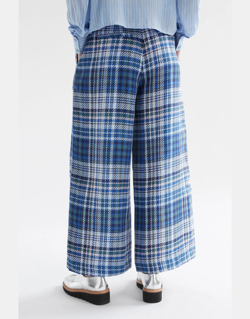 Elk Ranie Pant in blue multi-check pattern, casual pants with a relaxed fit, shown on a model in a natural outdoor setting.