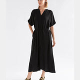 Black Elk Omia Shirt Dress hanging on a wooden hanger, showcasing its relaxed fit and classic shirt dress style.