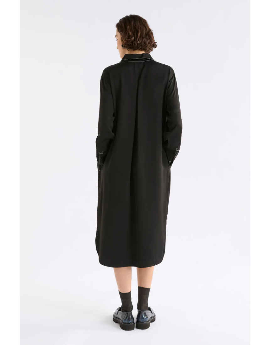 Black Elk Famke Dress hanging on a wooden hanger, showcasing soft fabric and stylish design.
