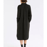Black Elk Famke Dress hanging on a wooden hanger, showcasing soft fabric and stylish design.
