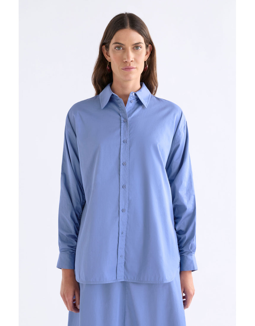 ELK The Label Dusk Blue Sol Shirt, a stylish blue top with a relaxed fit, displayed on a hanger.