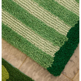 Reversible green bath mat with striped pattern by Bonnie and Neil, shown in a bathroom setting.