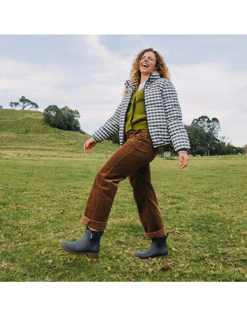 Merry People Bobbi gumboots in charcoal color, stylish waterproof rubber footwear worn outdoors in a natural setting.