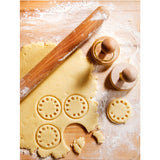 Suck UK customizable cookie stamp with engraved design, shown pressed into cookie dough for personalized baked treats.