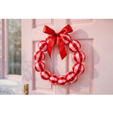 Little Fish Co silk ball Christmas wreath in red and pink with festive silk ornaments, displayed hanging on a door.