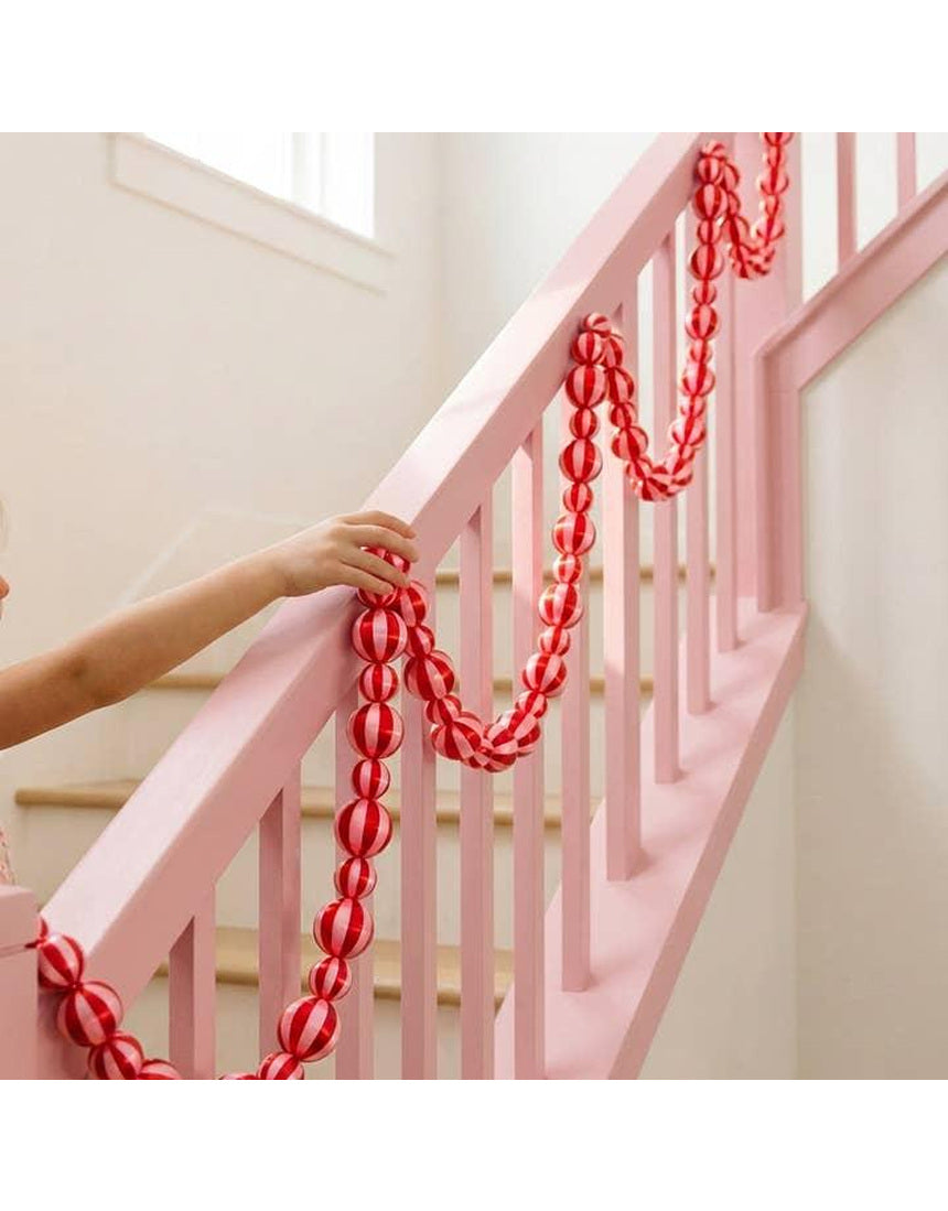 Pink and red satin Christmas garland by Little Fish Co, featuring striped design, displayed hanging in a festive setting.