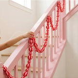 Pink and red satin Christmas garland by Little Fish Co, featuring striped design, displayed hanging in a festive setting.