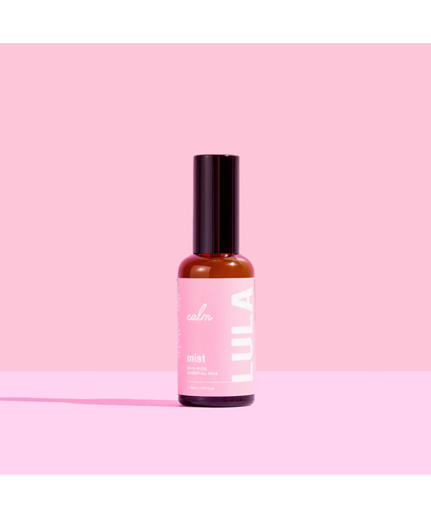 Lula Calm Mist essential oil bottle with a white label and pump spray nozzle, surrounded by calming greenery and soft lighting.