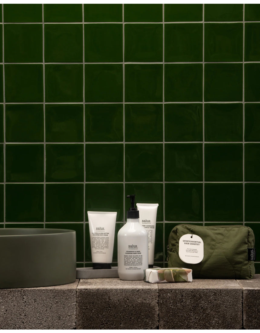 Salus Quintessential Skin Quartet set with four skincare products displayed in sleek bottles and jars.