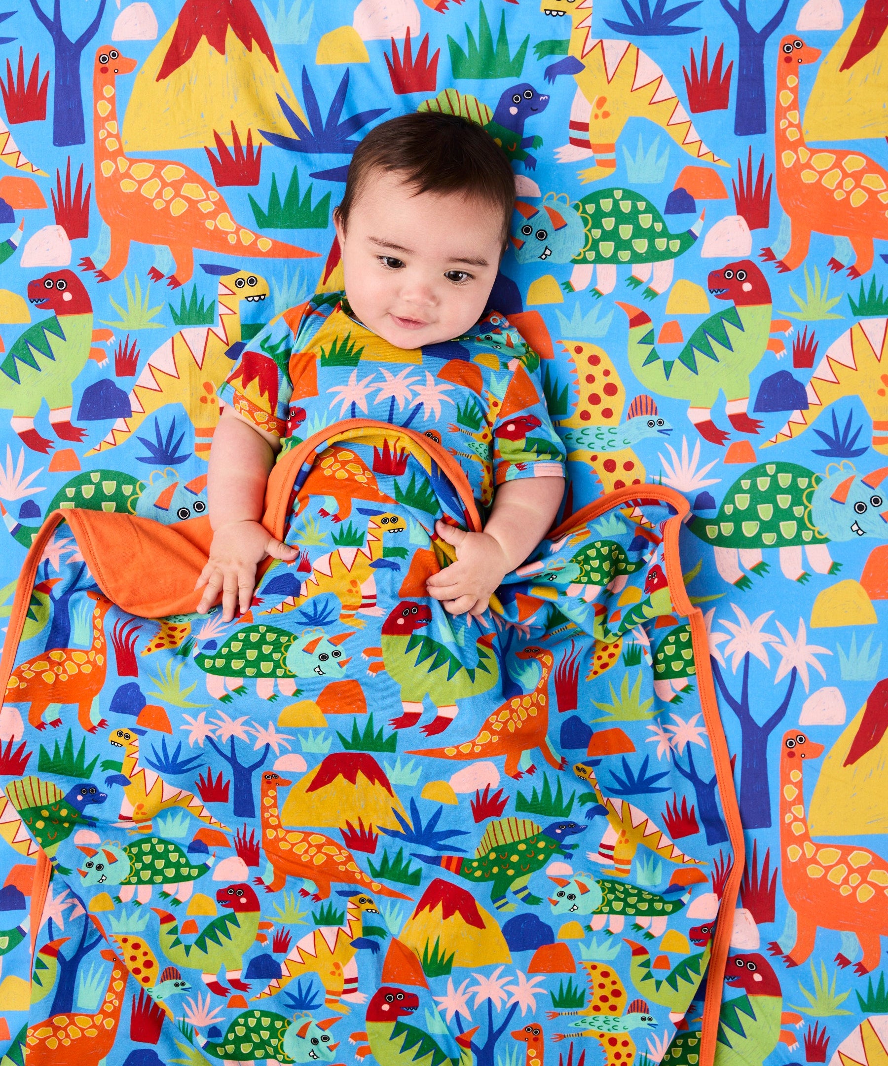 Kip & Co Dinosaur Roar organic cotton baby blanket with colorful dinosaur print, soft and cozy for infants.