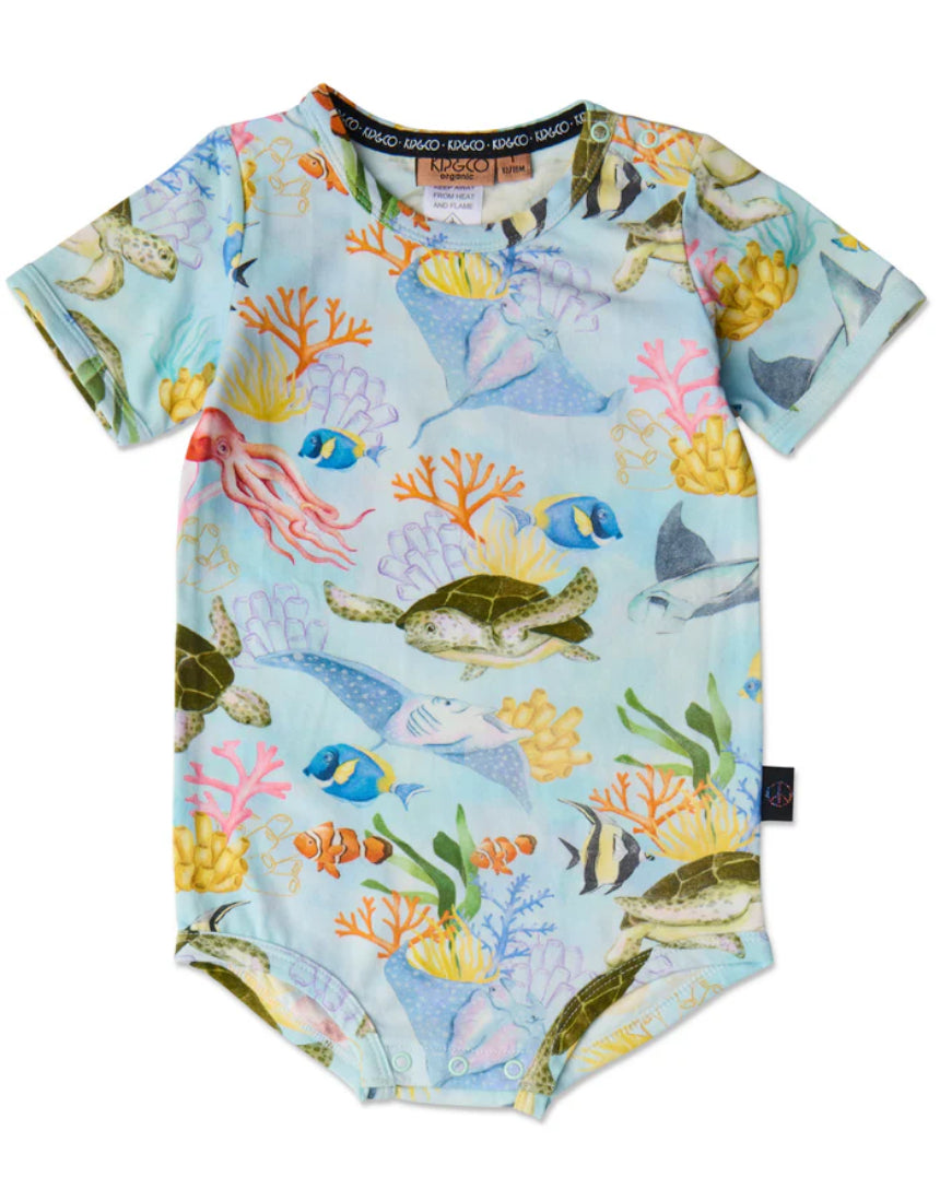 Baby wearing Kip & Co Reef Life short sleeve romper with colorful tropical print, short sleeves, and comfortable fit.