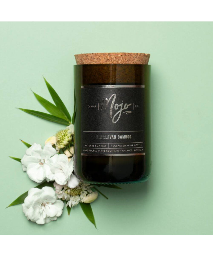 Himalayan Bamboo Black Label candle by Mojo Candle Co. with bamboo-themed packaging and a black label, flat lay arrangement.