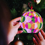 Hands holding Huxter Green Hanging Lip Balm on a Christmas tree