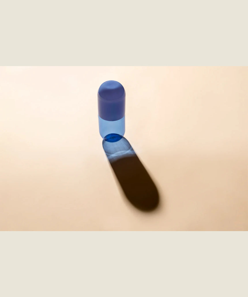 Maho Happi Pill into the Blue glassware with blue and clear design, featuring a cylindrical shape and decorative pattern.