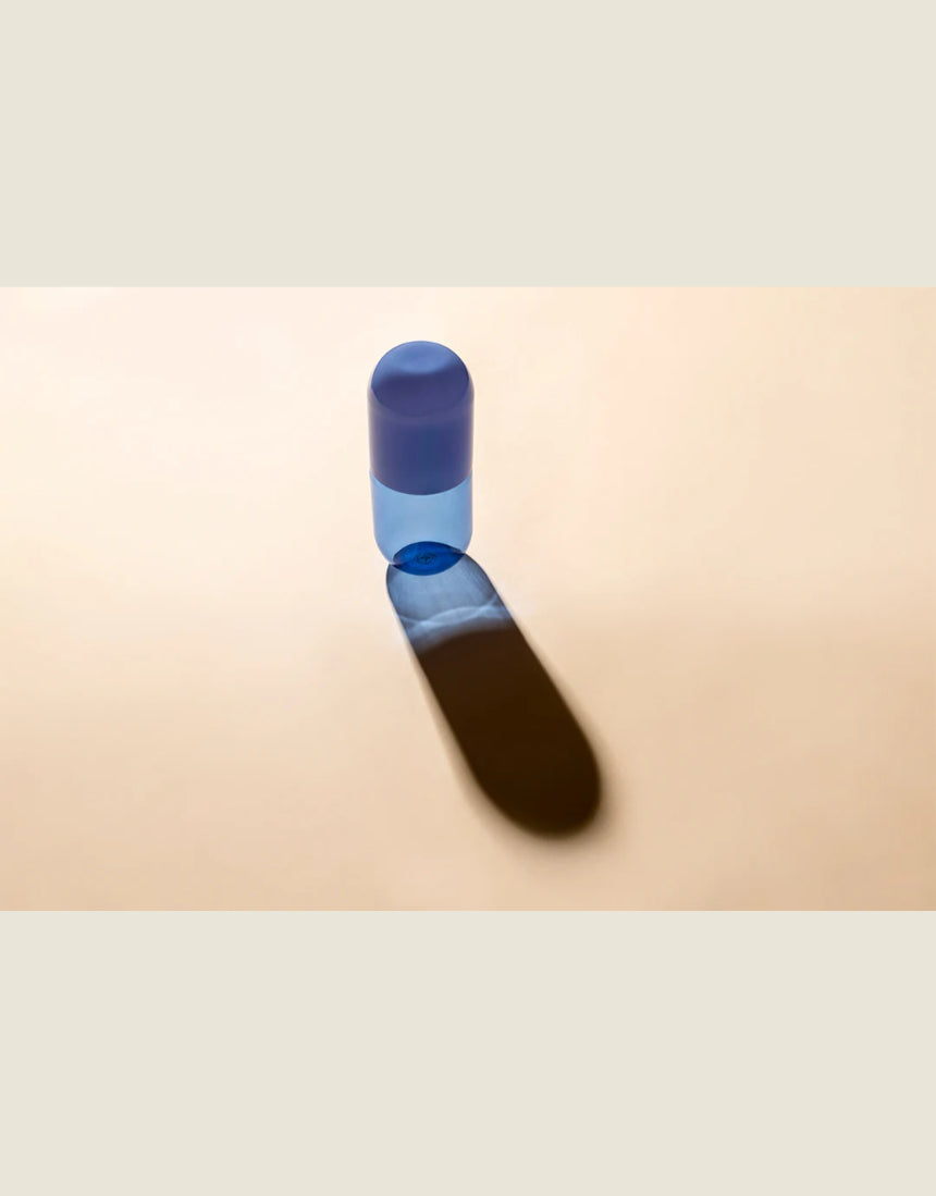 Maho Happi Pill into the Blue glassware with blue and clear design, featuring a cylindrical shape and decorative pattern.