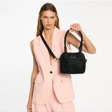Black Status Anxiety Mini Mountains Bag with adjustable strap, shown in a lifestyle setting with casual accessories.