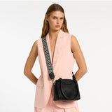 Black Status Anxiety Mini Mountains bag with adjustable strap and minimalist design, shown with casual outfit in lifestyle setting.
