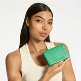 Status Anxiety Is Now Better Wallet in emerald green, showing its compact design and multiple card slots.
