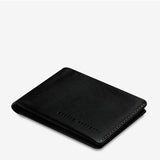 Black Status Anxiety Otis Wallet with sleek leather design, top-angle view showing card slots and compact wallet shape.