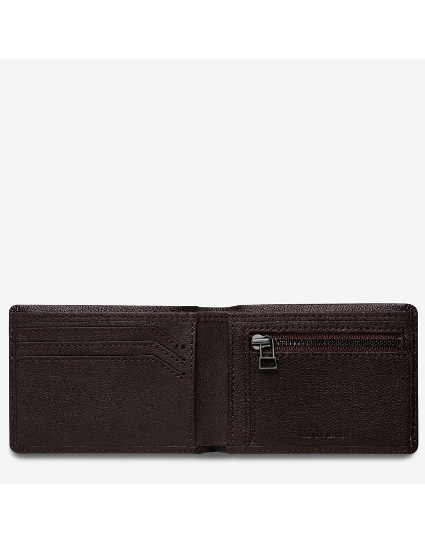 Open Status Anxiety Otis Wallet in chocolate brown, displaying multiple card slots and cash compartment on a flat surface.