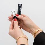 Suzy Lipsticks Miss Cassandra Peony Matte lipstick with a soft pink shade, shown in a sleek tube with the cap off.