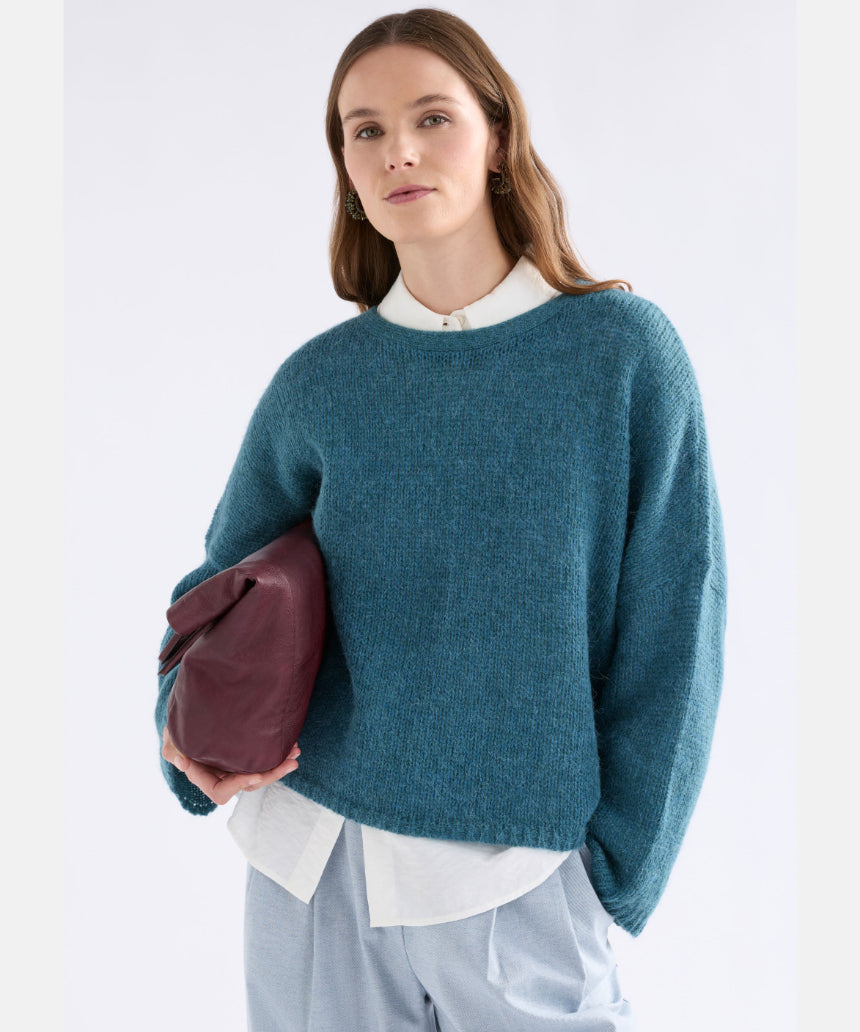Elk Agna Sweater in stone blue, soft knit fabric, displayed on a hanger, showcasing its cozy, casual clothing style.