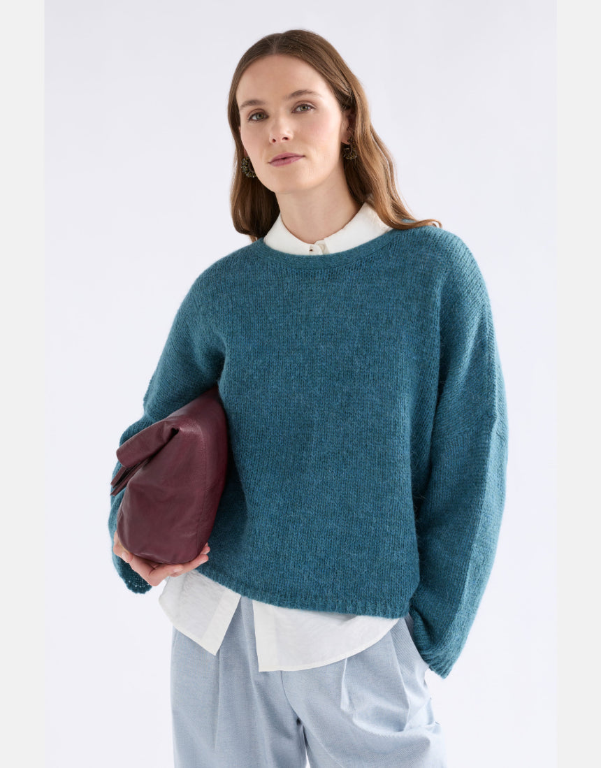 Elk Agna Sweater in stone blue, soft knit fabric, displayed on a hanger, showcasing its cozy, casual clothing style.