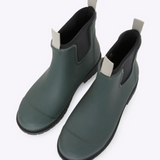 Forest green Merry People Bobbi gumboots shown on a person, featuring glossy waterproof rubber and sturdy soles.