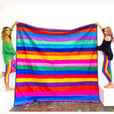 Riley Burnett picnic rug with colorful carnival stripe pattern, outdoor blanket for picnics and gatherings on grass or sand.
